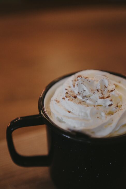 a cup of whipped cream sitting on top of a wooden table