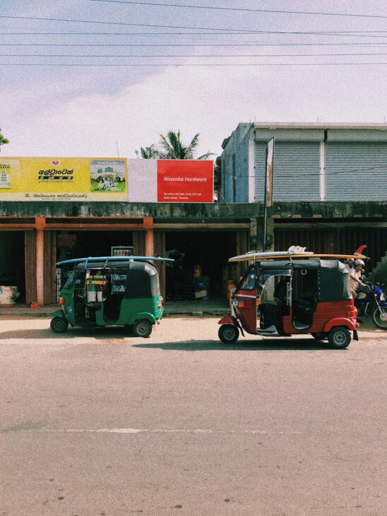red and black auto rickshaw parked beside white building