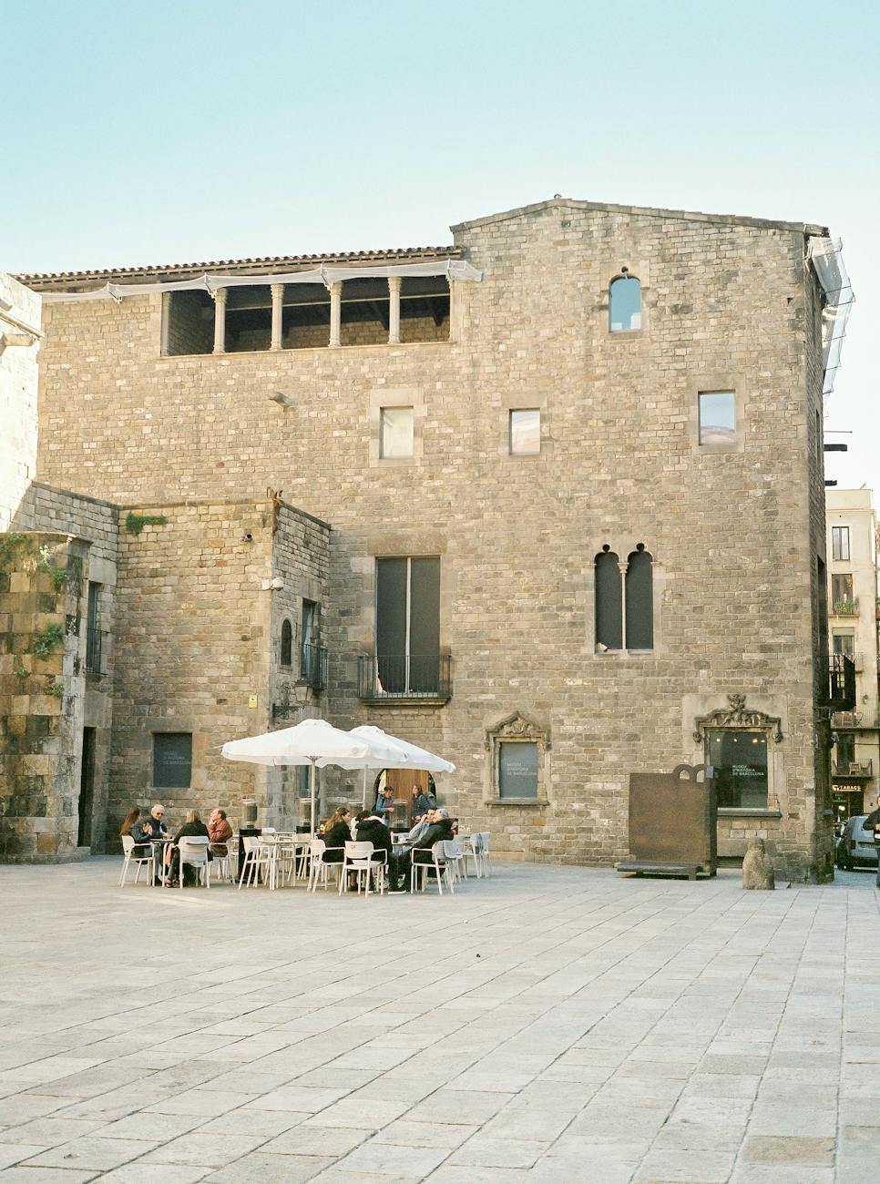 people sitting on white chairs near brown brick building