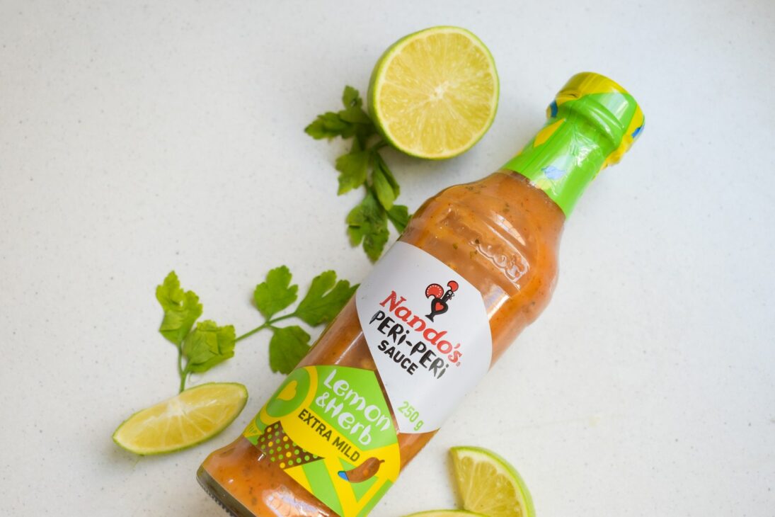 a bottle of ketchup next to sliced limes and cilantro 7 Things You Didn’t Know About Nando’s