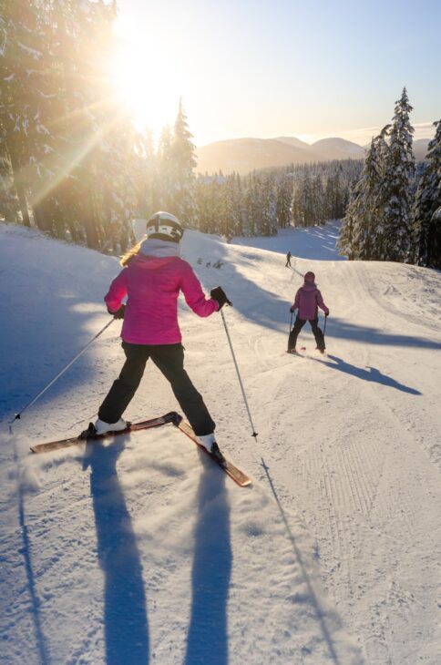 A couple of people riding skis down a snow covered slope