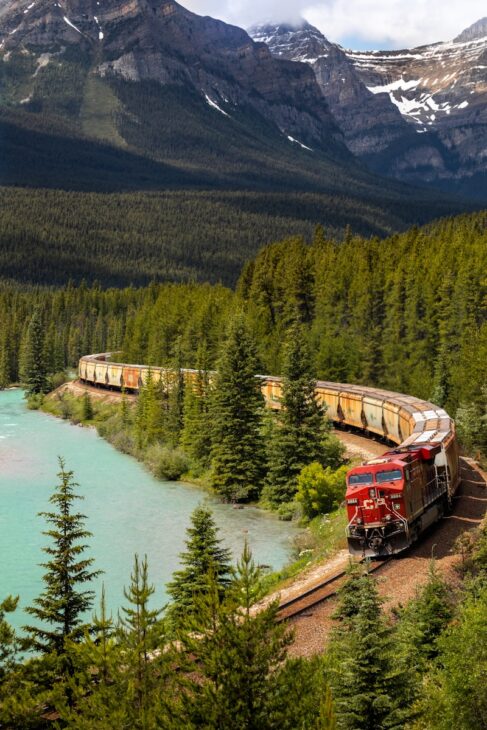 red and white train on rail near body of water during daytime