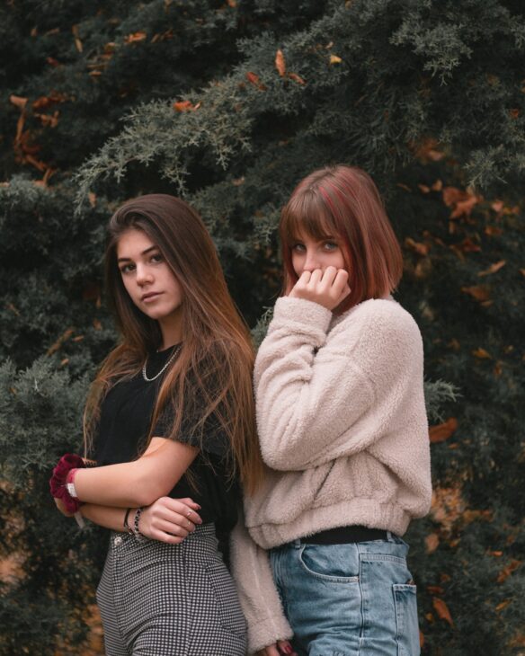 two women in black and beige top standing beside plant